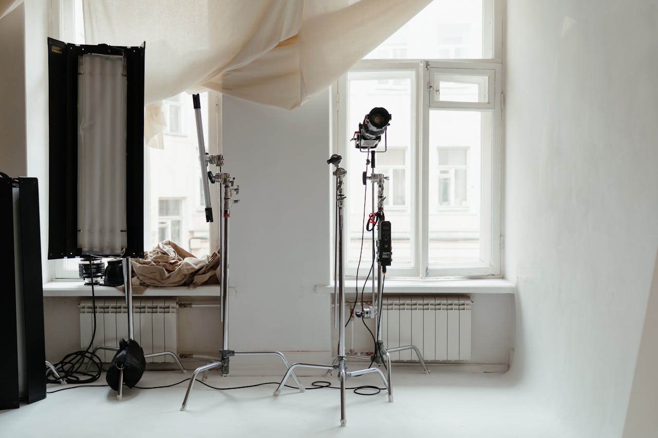 A minimalist photo studio setup with professional lighting gear and natural light from windows.